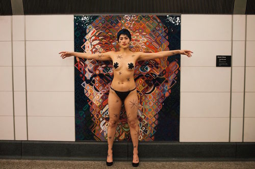 [Image: Emma Sulkowicz’s protest performance, with a Chuck Close mosaic at the Second Avenue subway 86th Street station, photo by Sangsuk Sylvia Kang]